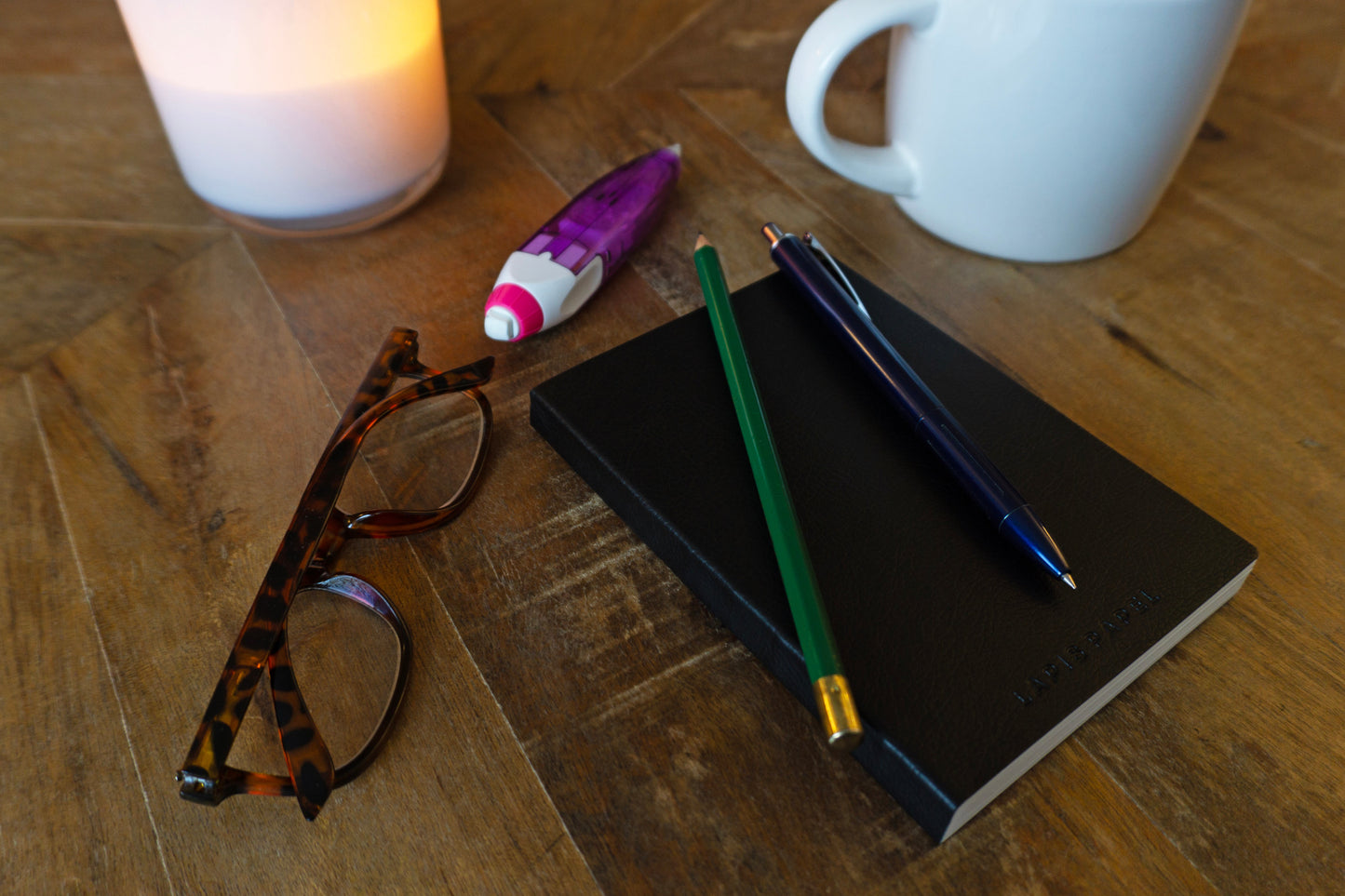 Black A6 notebook on wood surface with pencil and pen