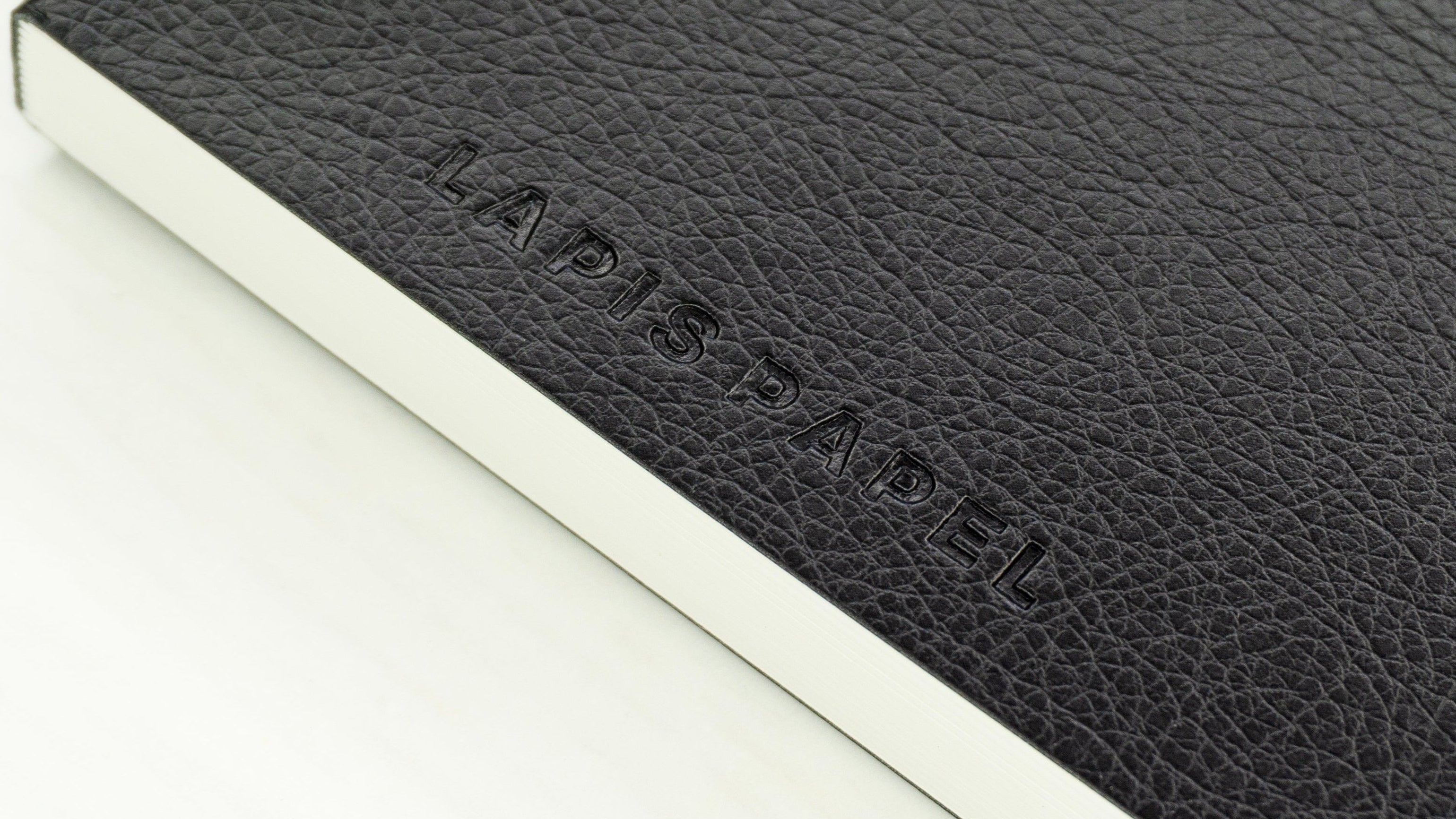 Black A6 notebook with embossed "Lapis Papel" logo on white background